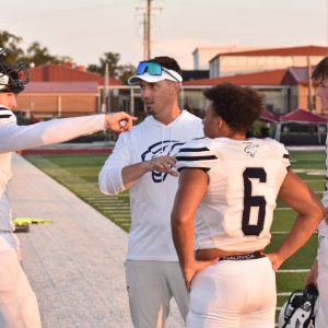 Senior Ka'Den Blackston and junior Gage Stinson listen closely as senior quarterback Coby King and his father, head coach and offensive coordinator Michael King talk about a play call during action earlier this season. Photo by RUSSELL TURNER | Herald Editor